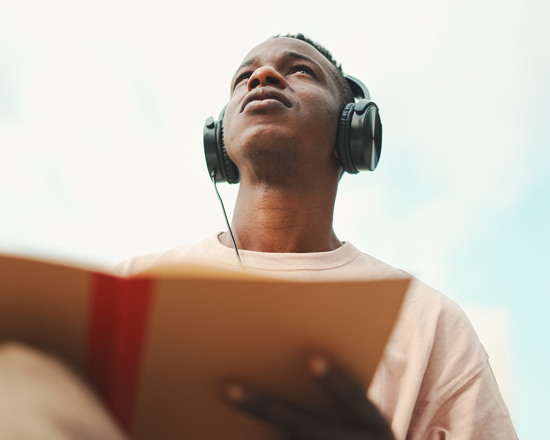 man with headphones reading a book enjoying peaceful moments outdoor relaxation and learning